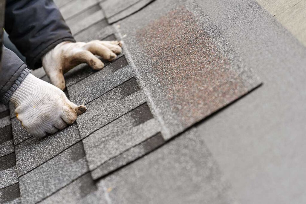 Close-up of curled and cracked asphalt shingles on a residential roof after seasonal weather exposure