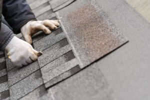 Close-up of curled and cracked asphalt shingles on a residential roof after seasonal weather exposure